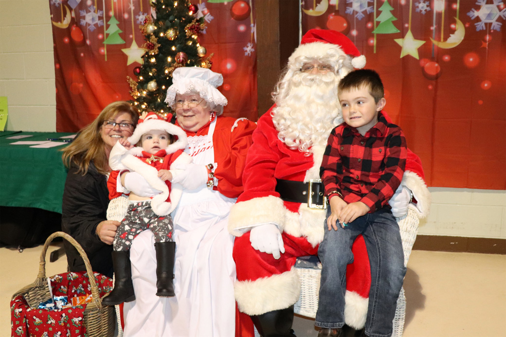 Kaden and Kailey sit with Santa and Mrs. Claus at the Hoilday Bazaar.