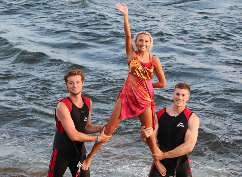 Shane and Kyle lift Emma to wave to the crowd after their water ski act.